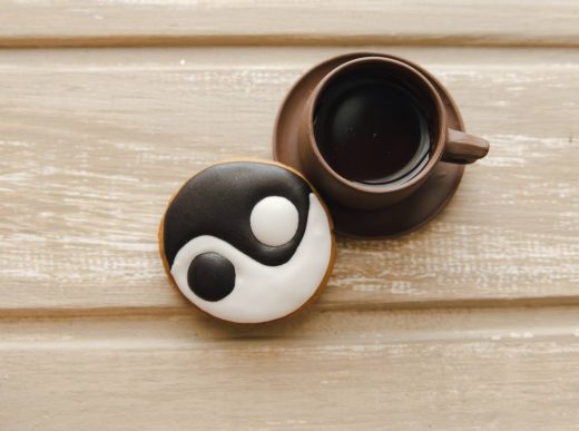 Кофе в керамической чашке и печенье с символом инь-ян на деревянном столе – отражение энергий марта 2025